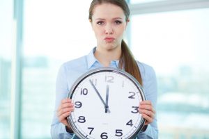 Mujer preocupada sujetando un reloj de pared