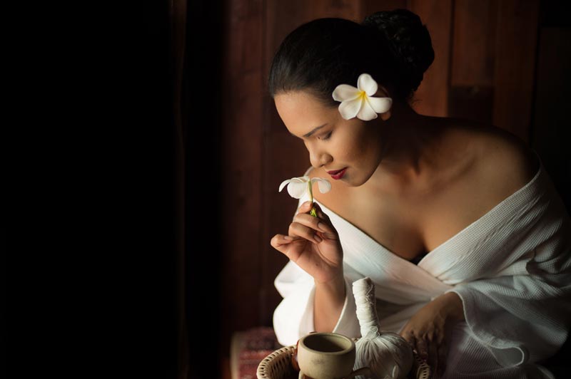 Mujer oliendo una flor en un spa