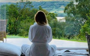 Mujer sentada en túnica blanca mirando las montañas durante el día
